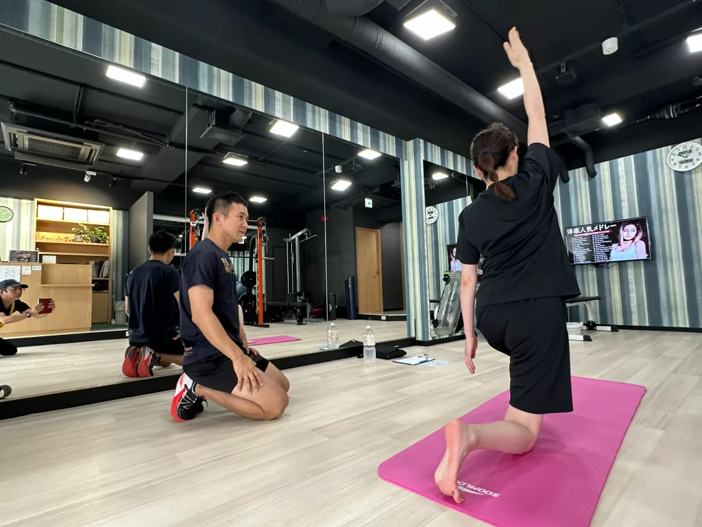 ジムにてトレーナーが、お客様にトレーニング指導している