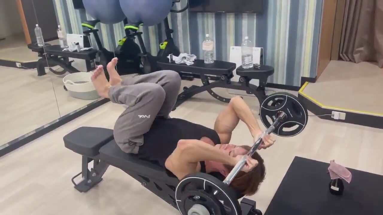 ベンチプレスを持ち、鍛えるトレーナー